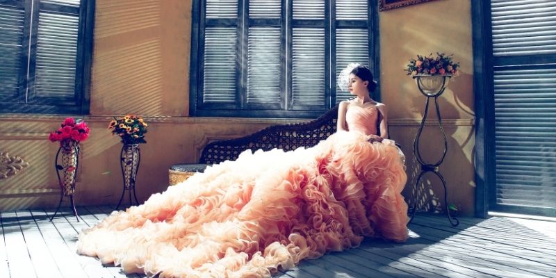 woman in elegant gown sitting on an indoor bench