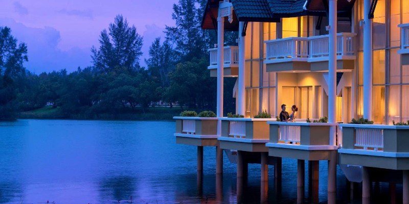 A man and woman stare out over the lake from their private balcony at Angsana Thailand resprt