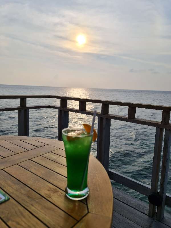 A green cocktail on a table overlooking the ocean in the Maldives
