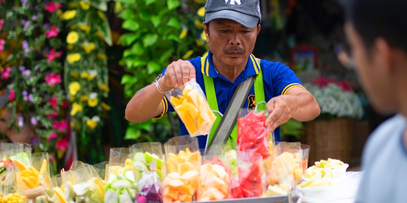 Man arranging gifts on a market stall in Bangkok