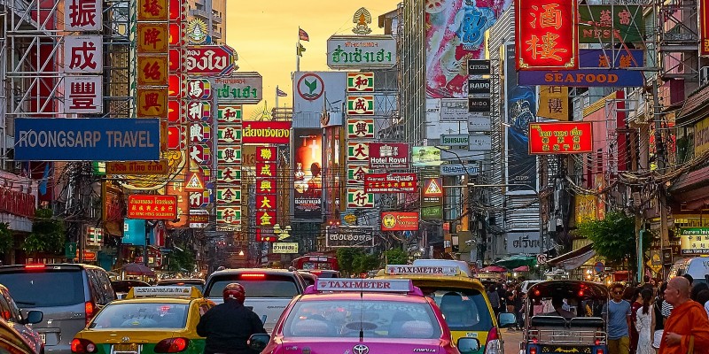 Taxi's, people and colourful signs on the streets of Bangkok