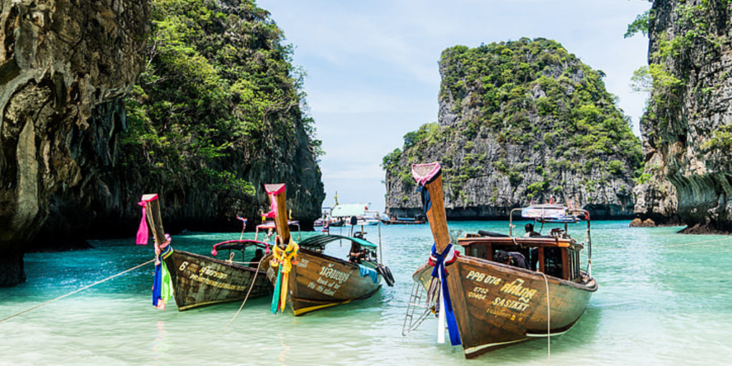 Three wooden boats on the shore of a beach in Thailand. 