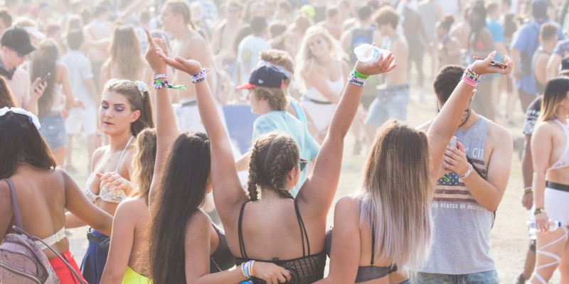 three girls pose for a picture at a busy beach party