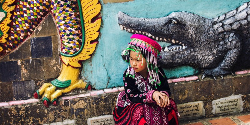 Thai girl sits in front of a wall mural