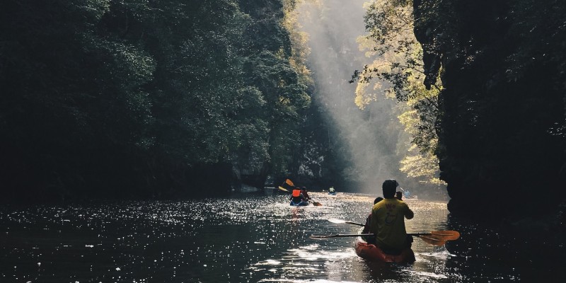 People canoeing along a river in Thailand