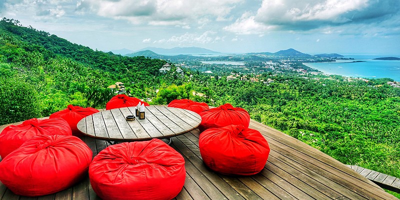 Table and bean bag chairs lookout out over the Thai jungle