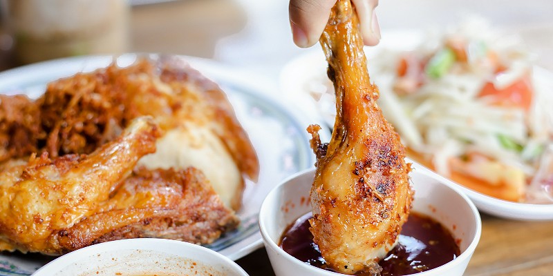 Person dipping a chicken leg into sauce